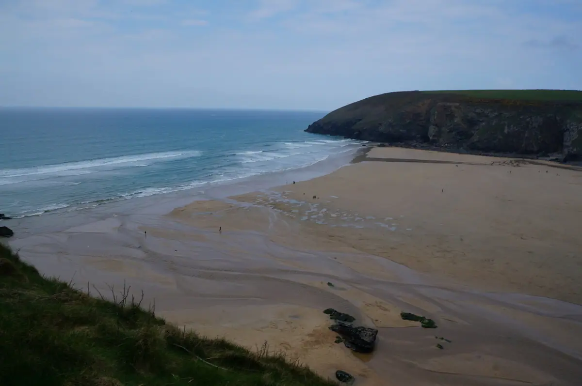 Mawgan Porth beach at low tide with the headland beyond